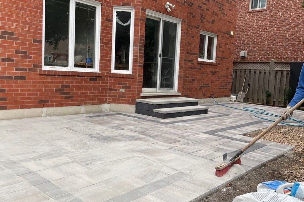 Sweeping in polymeric sand for maintenance on an interlocking patio in Mississauga, ON