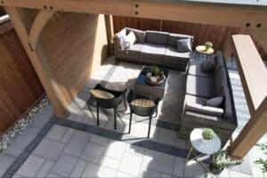 Covered backyard stone patio with herringbone interlocking pattern, lounge seating and cozy fall accessories.
