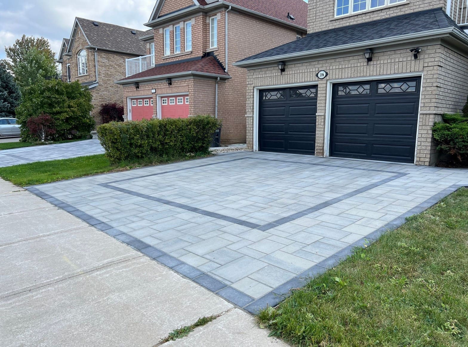Wide interlocking driveway installation featuring rectangular concrete pavers in a residential neighbourhood.