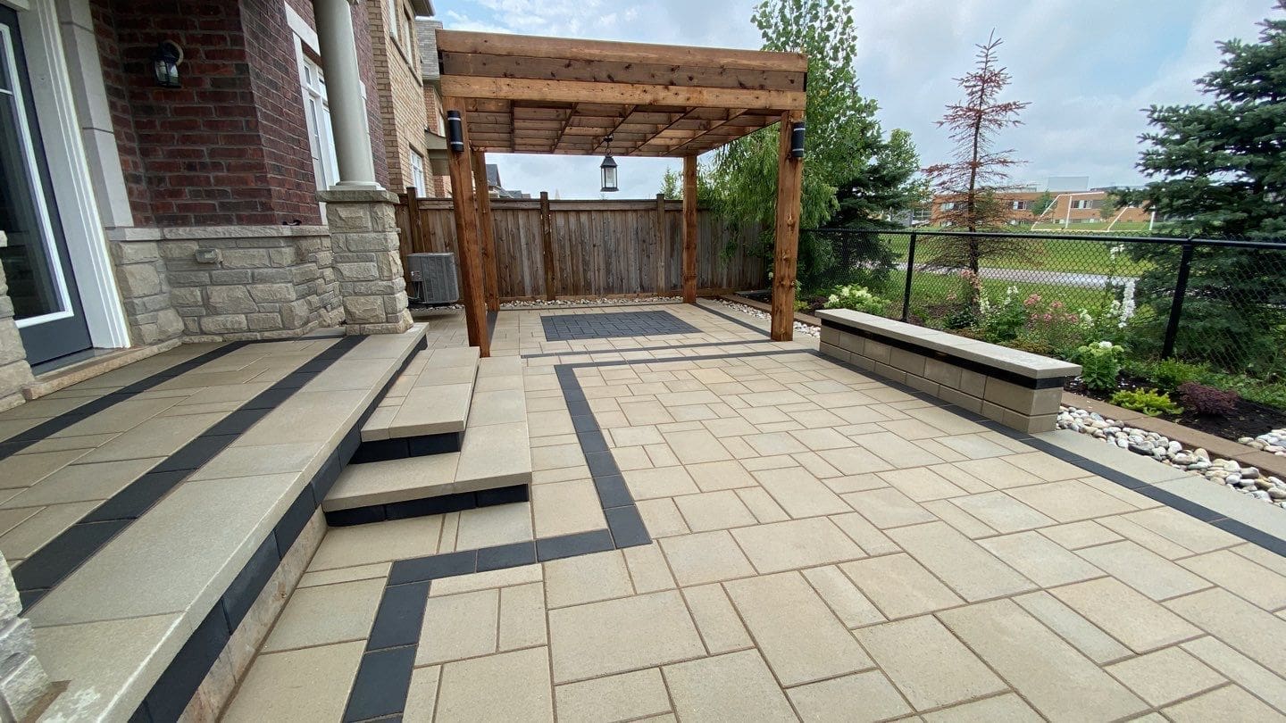 Interlocking stone patio with integrated steps and clean border detailing beside a residential home.