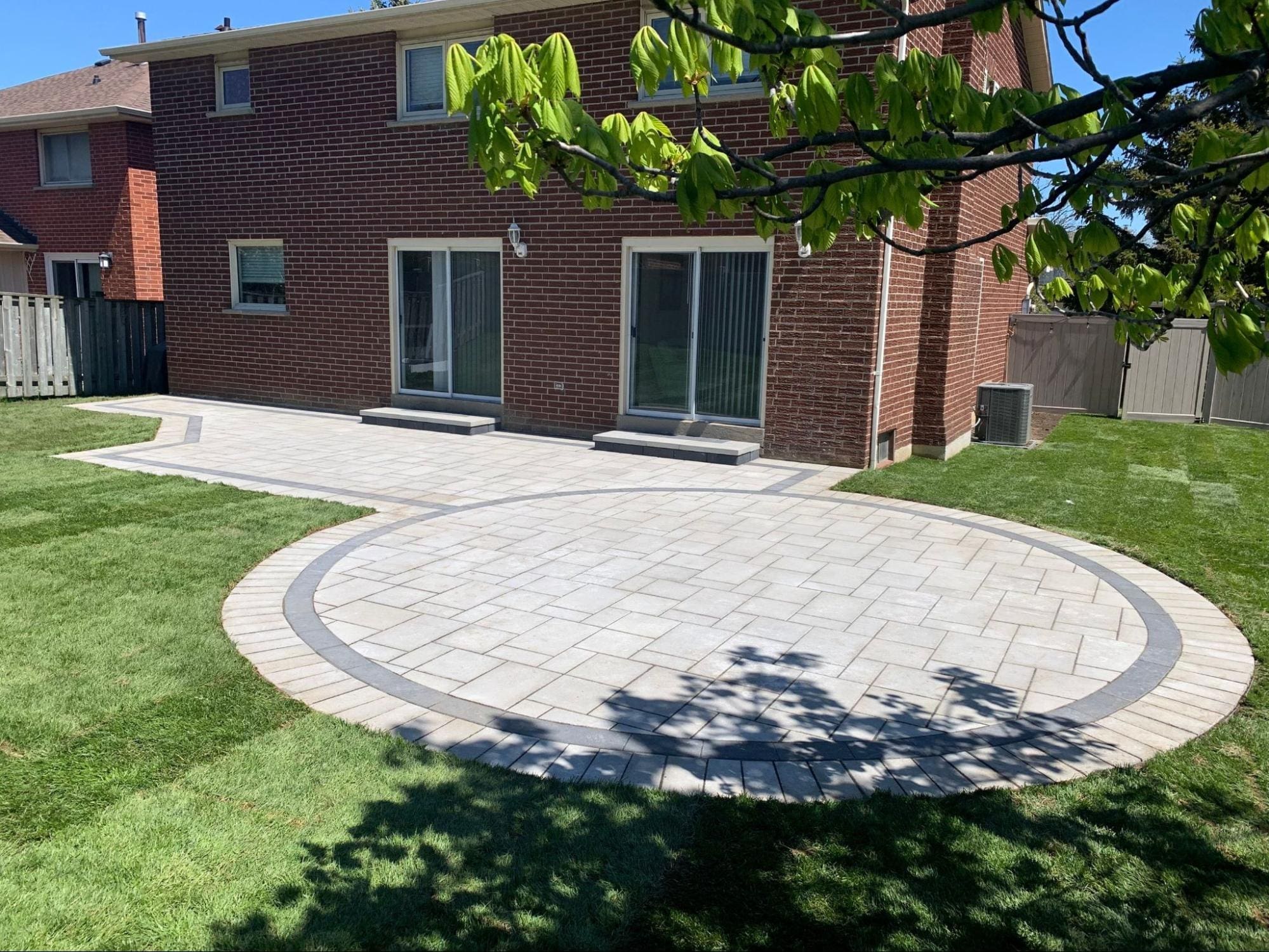 Curved interlocking patio with circular border in a landscaped backyard