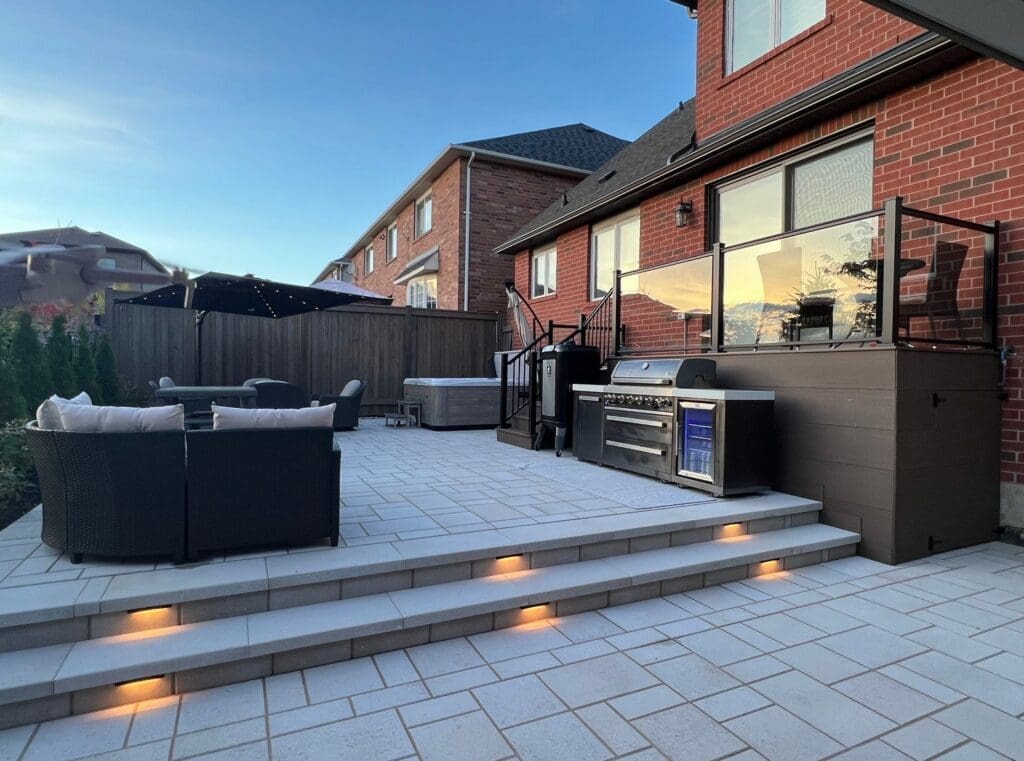 Modern interlocking patio design with steps, built-in lighting and outdoor kitchen.