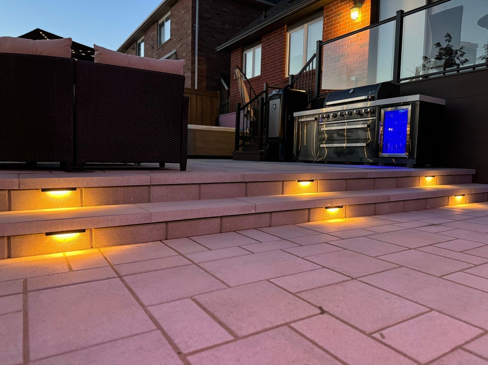 Backyard interlocking patio with landscape lighting for year-round outdoor enjoyment.