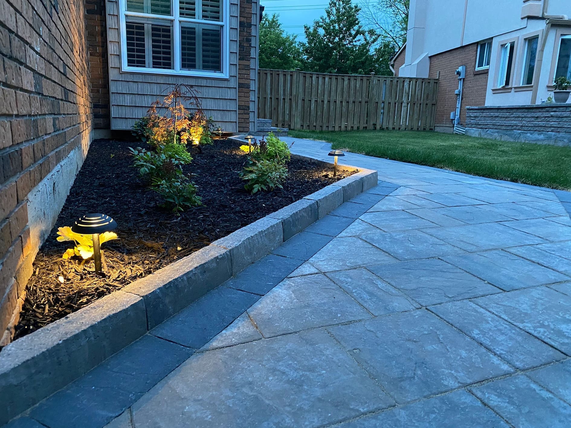 Landscape lighting along an Oakville interlocking walkway in a modern landscaping design.
