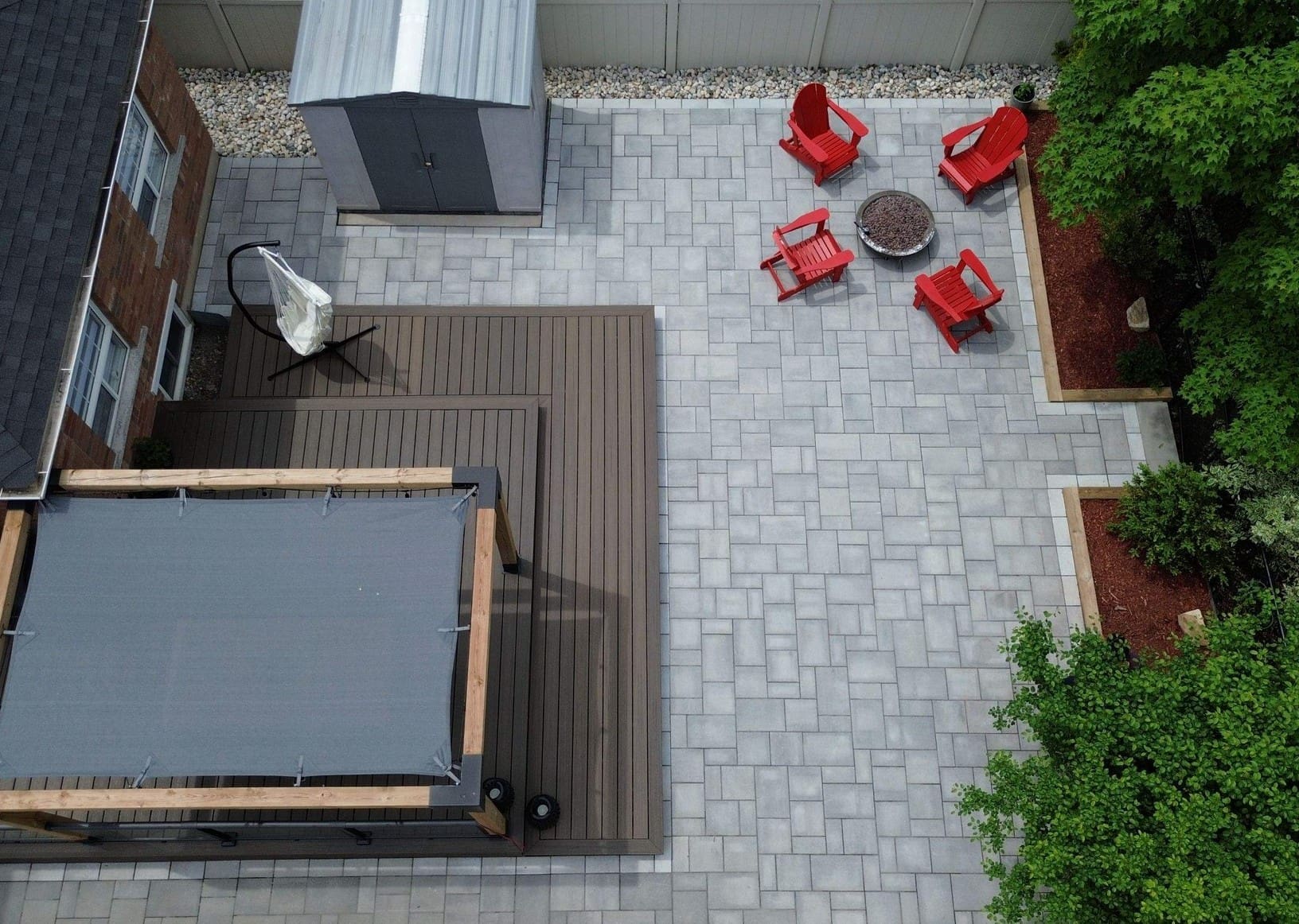 Interlocking backyard design with a compact covered seating area, multi-tone pavers and a cozy conversation layout with a firepit in the middle.