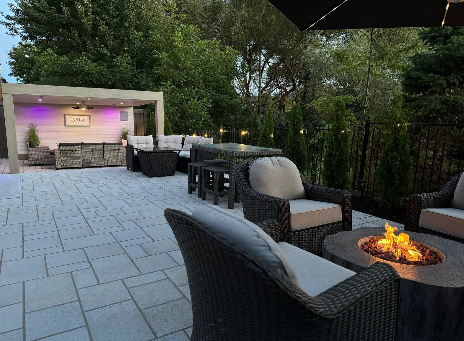 Backyard layout divided into activity areas with interlocking pavers, a deck, fire pit seating and defined planting zones.