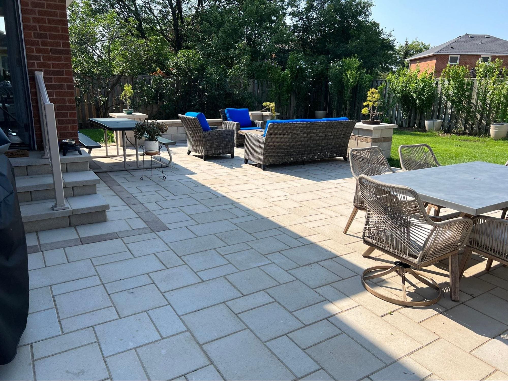 Backyard interlocking design separated into landscaped zones with stone pavers and greenery.